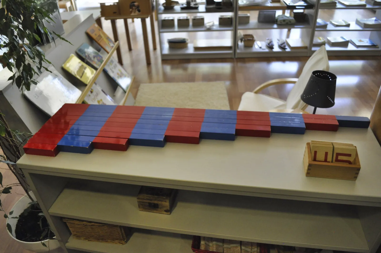 Red and blue number rods laid out on a low shelf in a Montessori environment